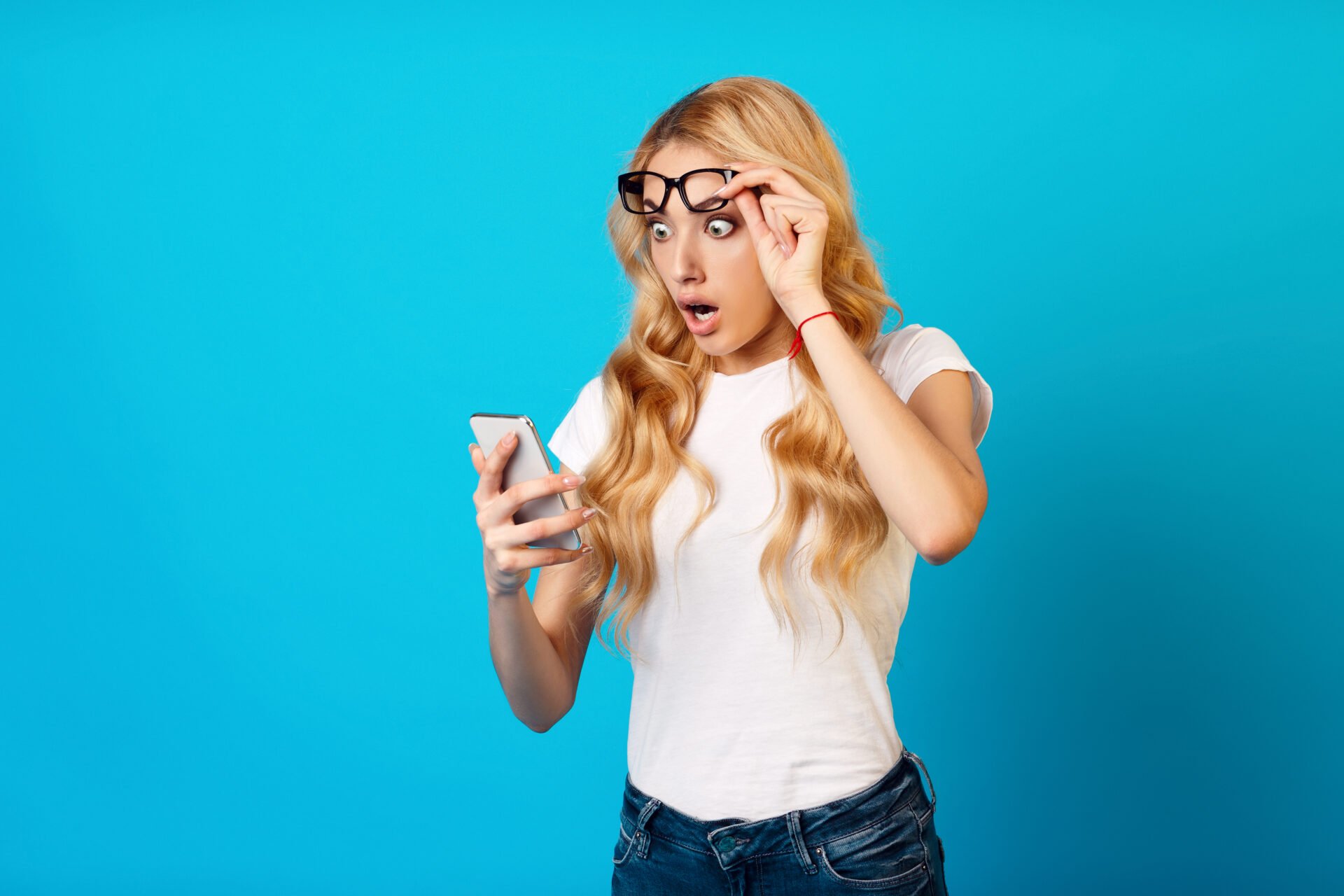 Shock Content. Woman Looking At Smartphone Over Blue Studio Background