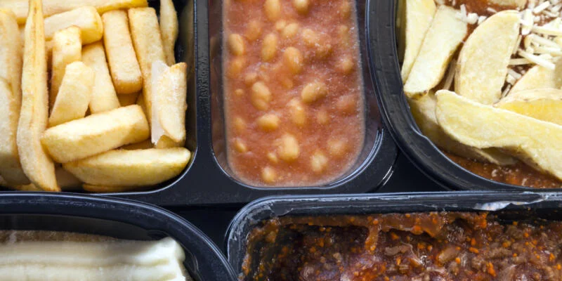 Selection of frozen, processed, ready made foods, consisting of potato chips, mince, lasagna in black, plastic containers . Microwave meals ready to heat up with a huge amount of phthalates
