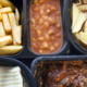 Selection of frozen, processed, ready made foods, consisting of potato chips, mince, lasagna in black, plastic containers . Microwave meals ready to heat up with a huge amount of phthalates