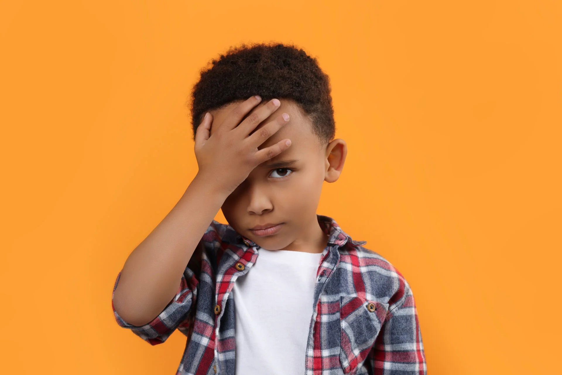 Portrait of emotional African-American boy on orange background