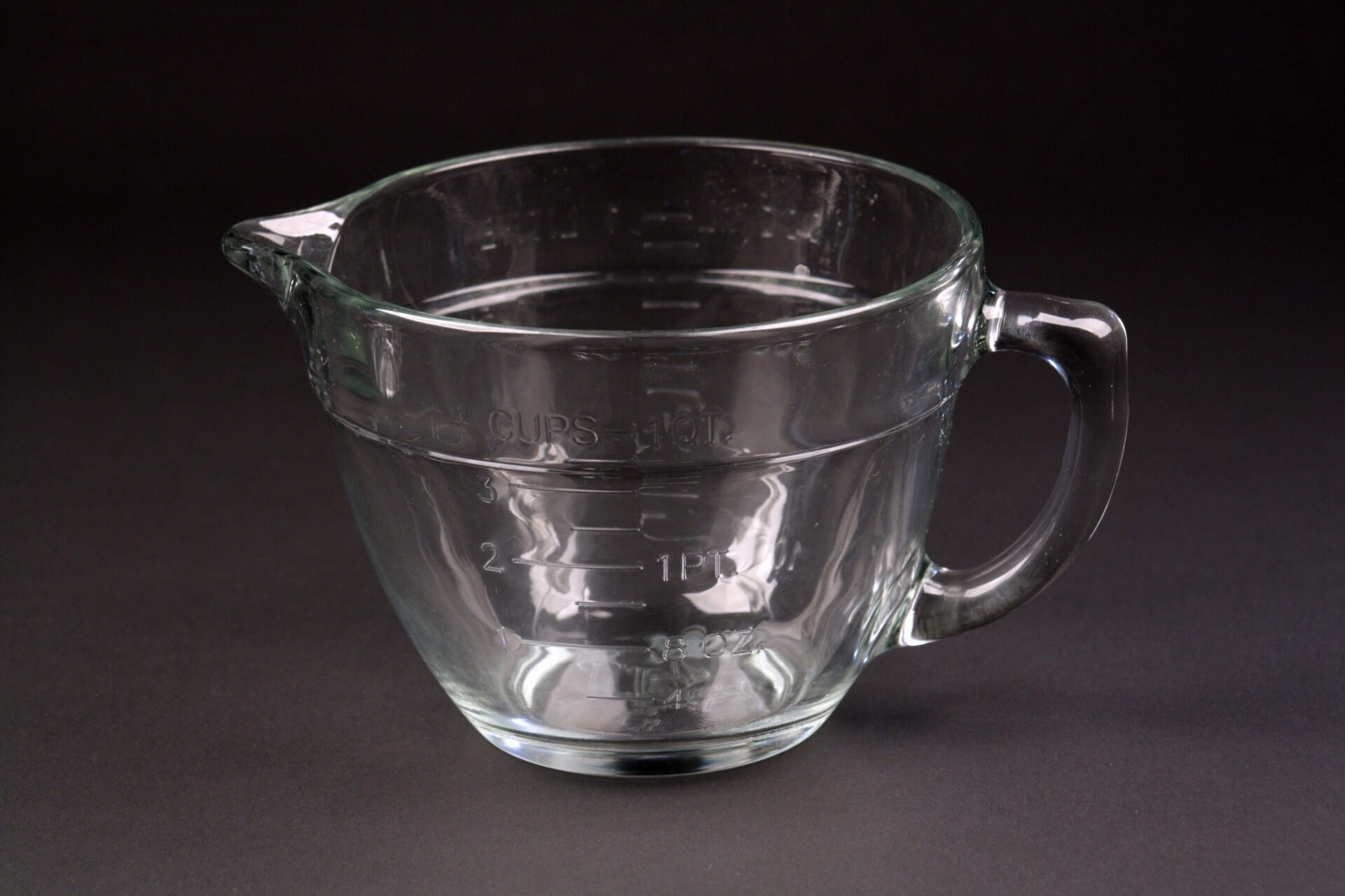 Glass measuring cups tested for lead on dark background