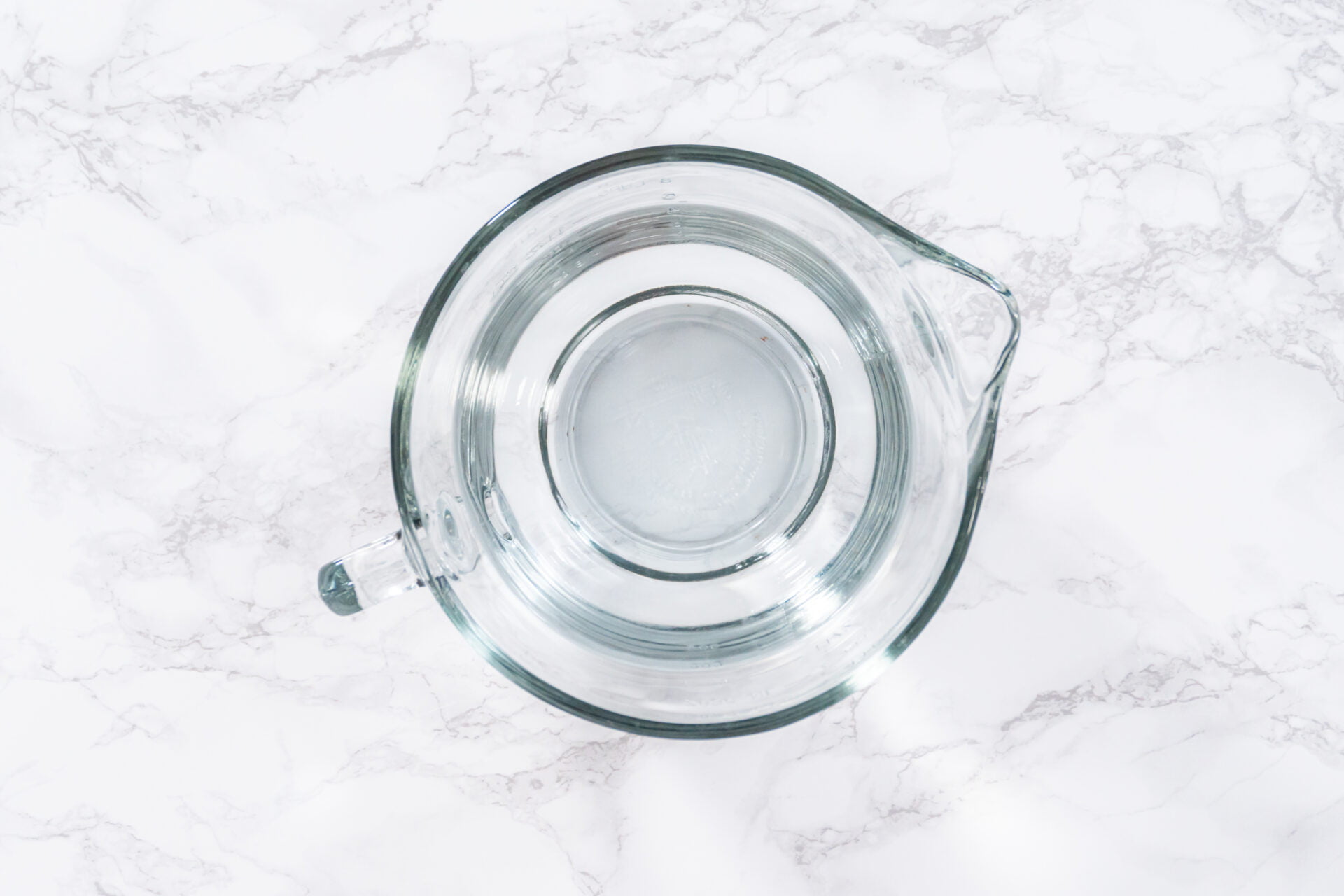 Glass measuring cups are filled with water, lined up and ready to be used in the careful washing of fresh strawberries, ensuring precise and thorough cleaning.
