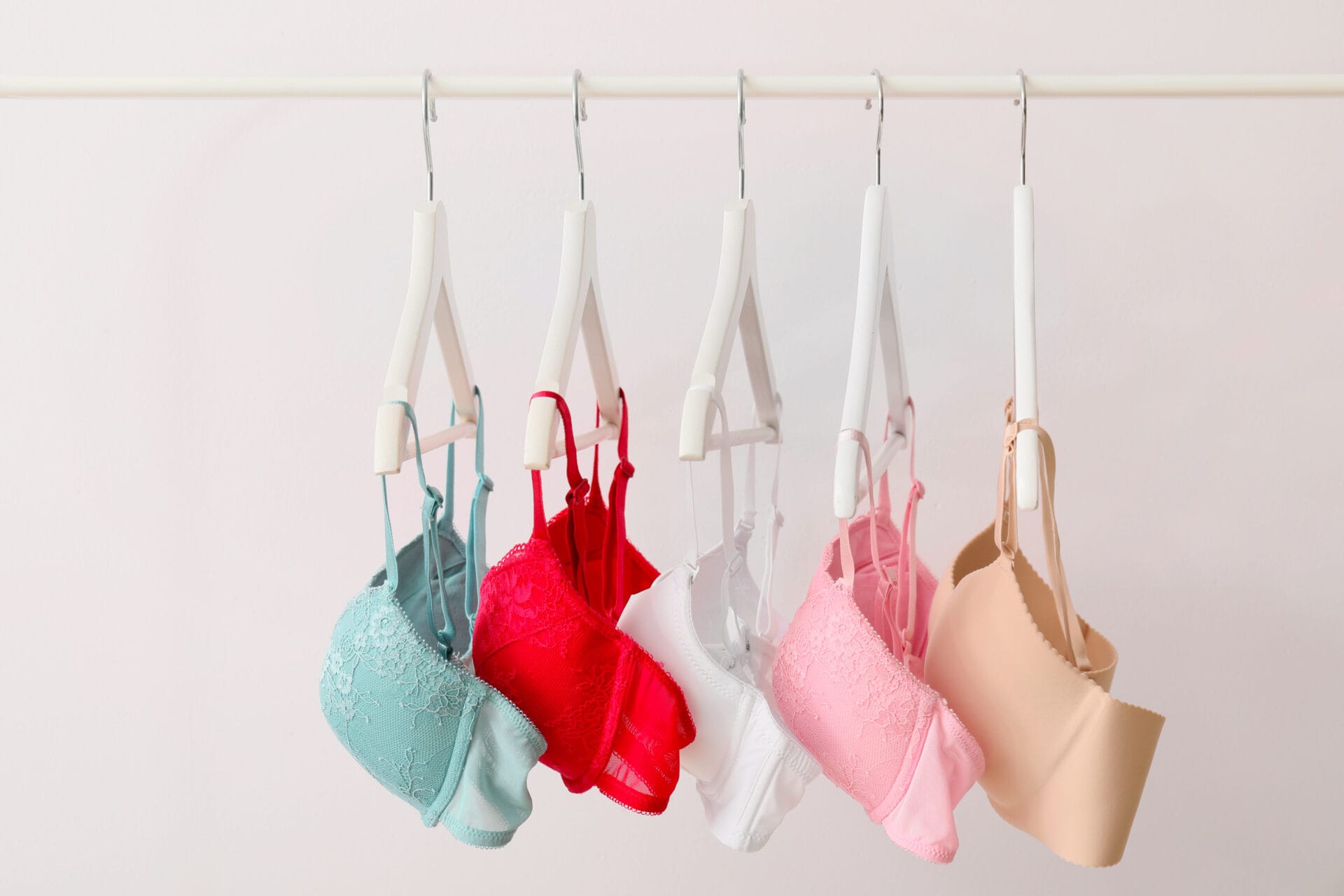 Clothes rack with stylish bras on light background