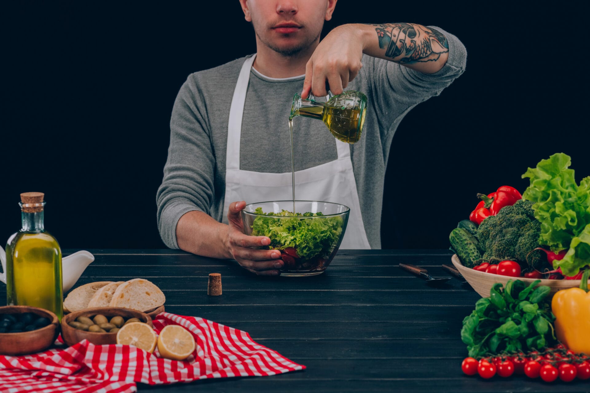 Man pouring cooking oil into a salad in the kitchen