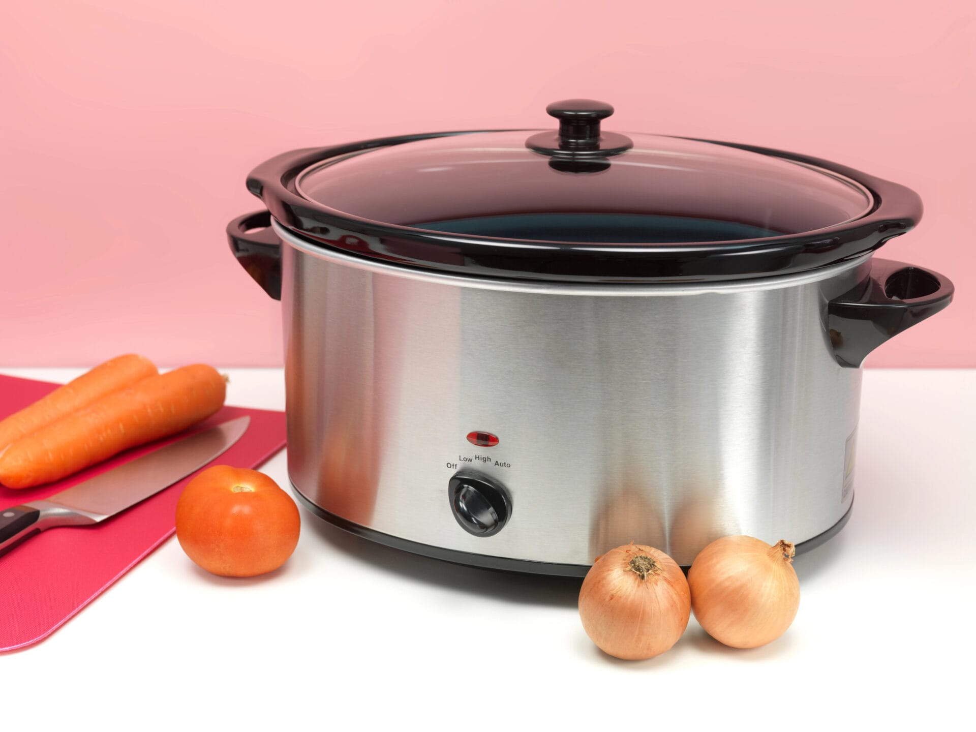 Slow cooker against a pink background