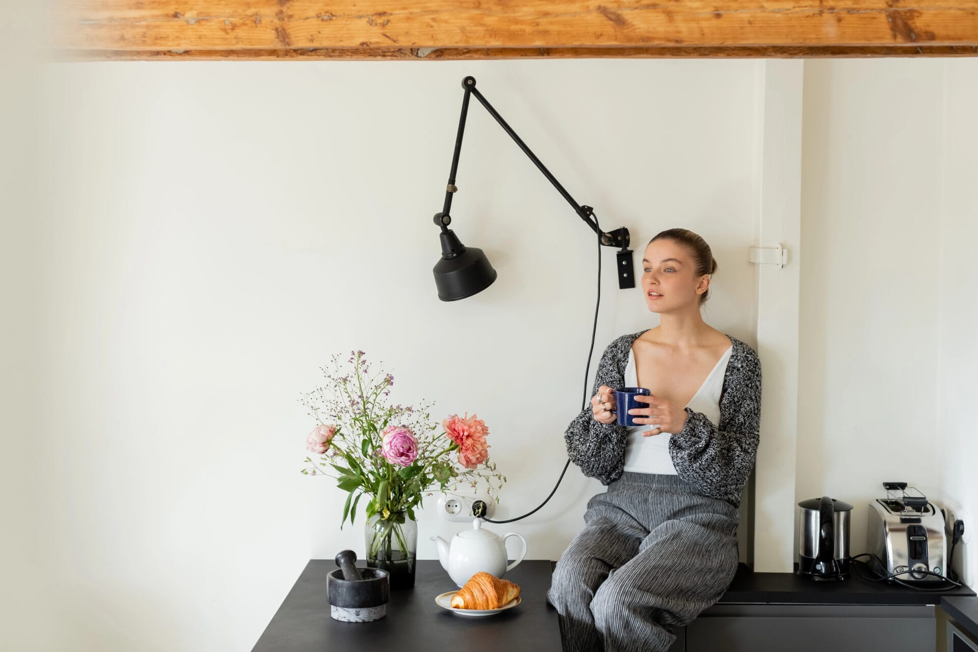 Woman drinking tea next to her electric tea kettle